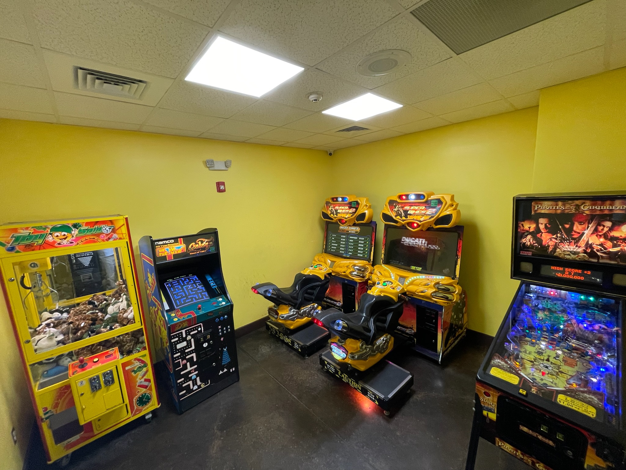 Arcade at Pirate's Cove — claw machine, Pac-Man, Super Bikes, and pinball