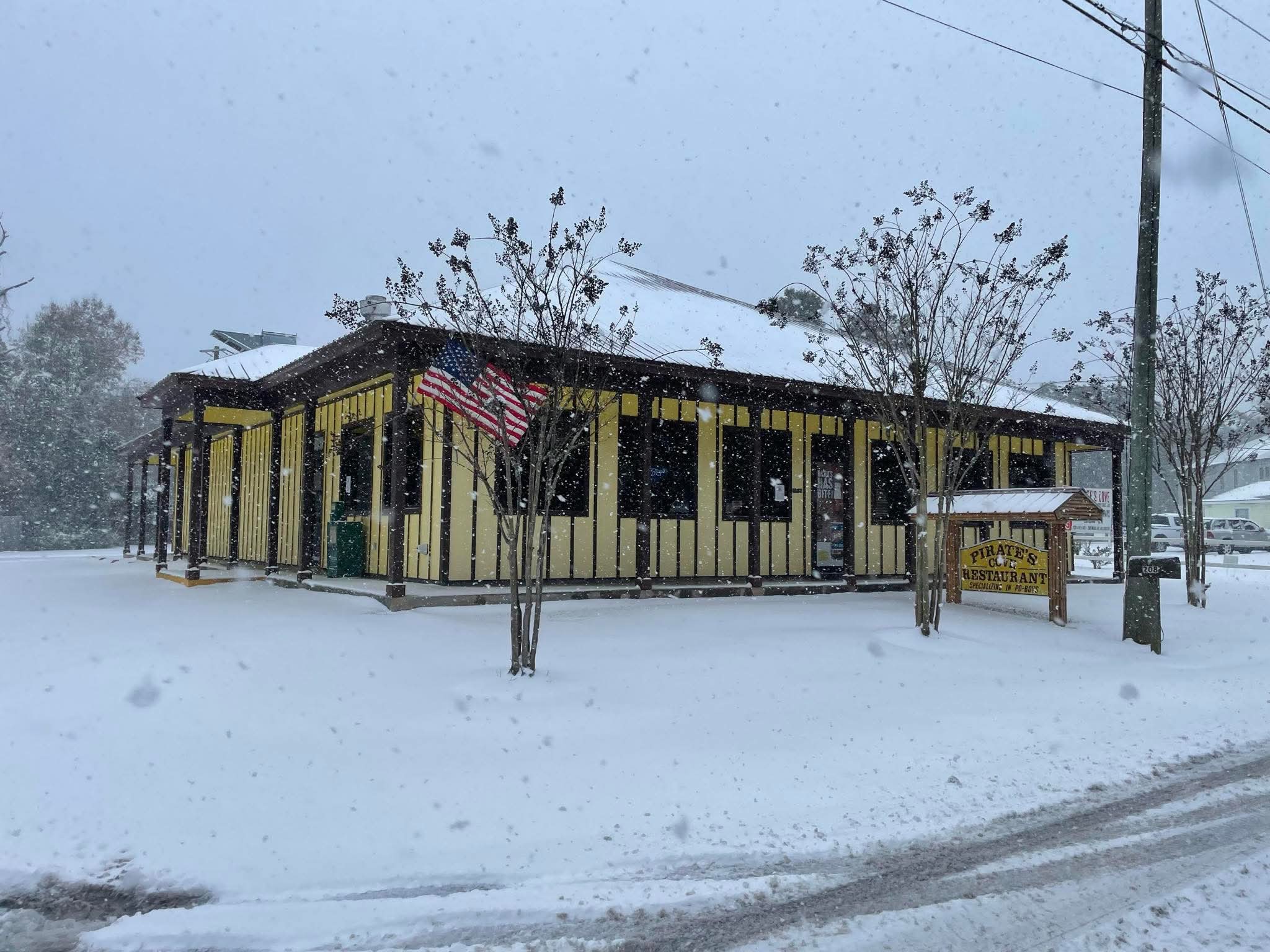 Pirate's Cove yellow building and roadside sign in the snow