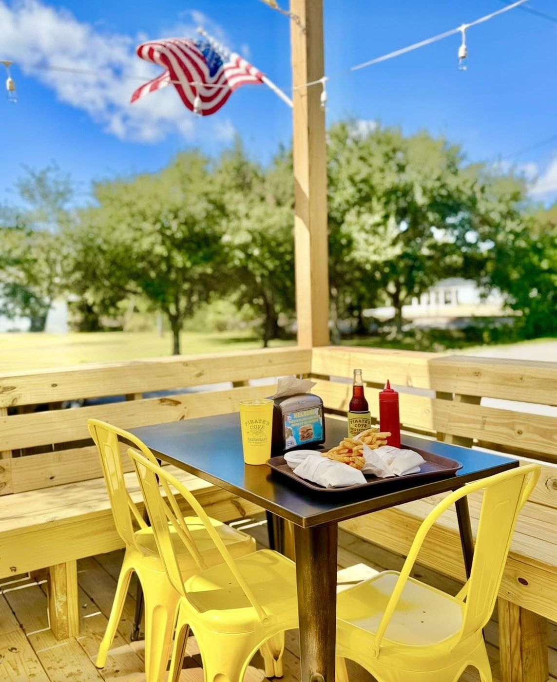 Po-Boys on the deck at Pirate's Cove with yellow chairs and the American flag